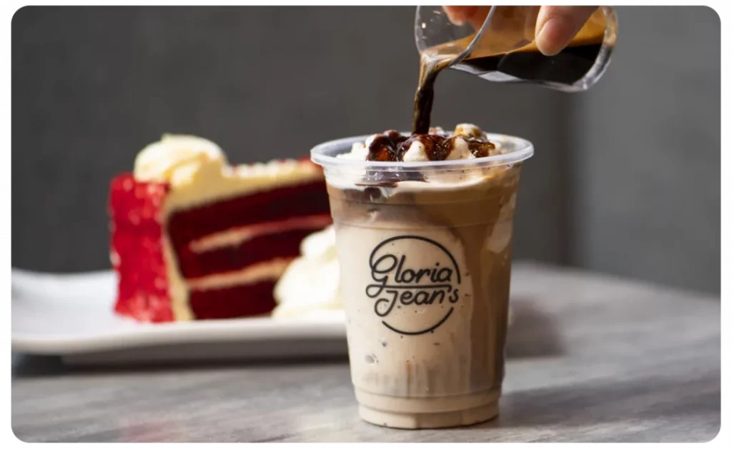 A person pouring coffee into a cup next to a cake at Gloria Jean's.