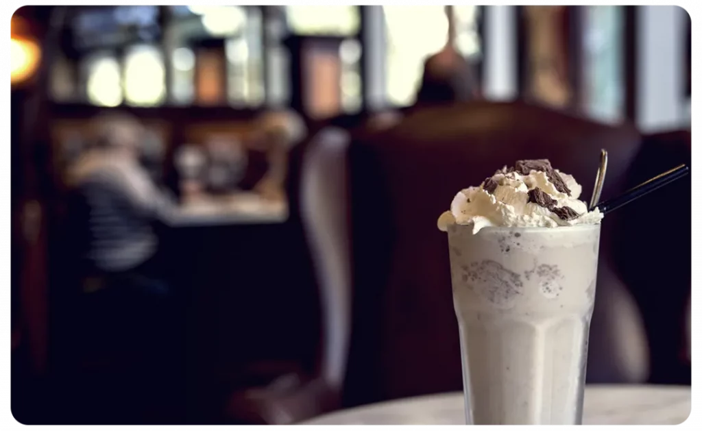 A milkshake sitting on a table in a restaurant.