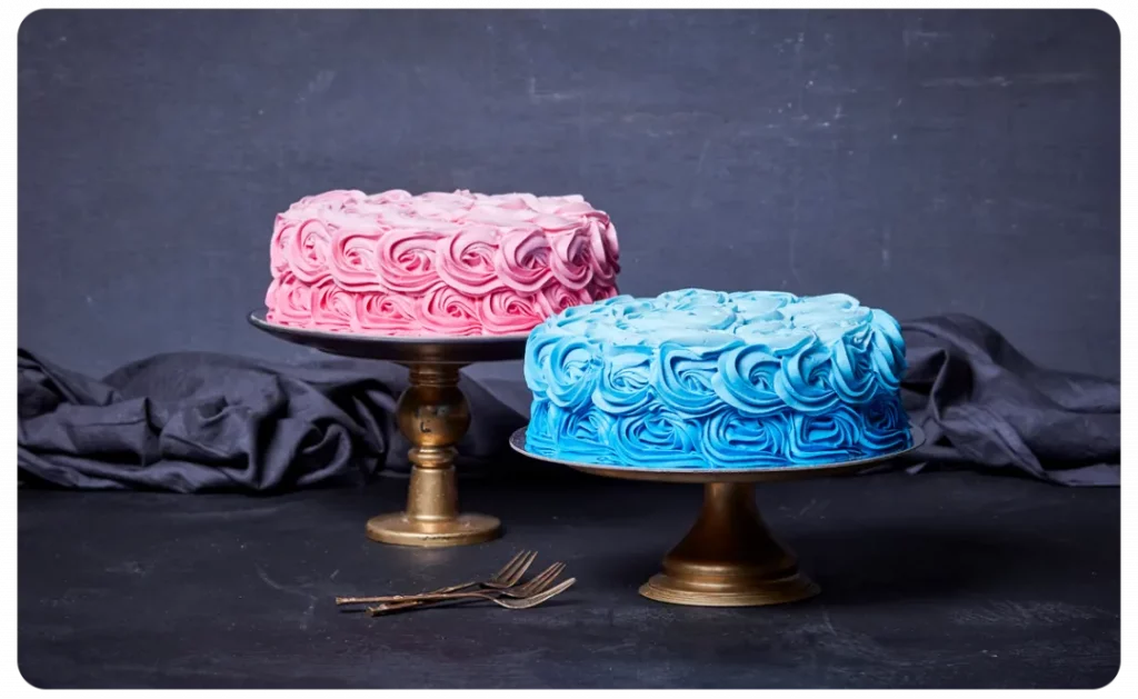 A pink and blue cake on a stand with a fork.