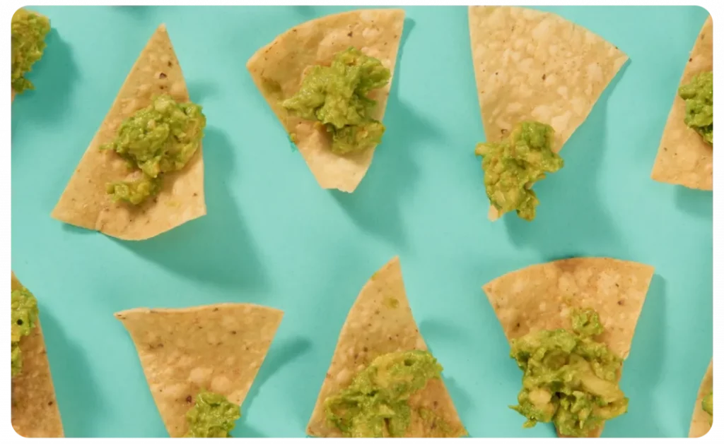 Guacamole and tortilla chips on a blue background.